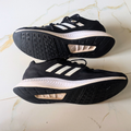 A pair of black Adidas running shoes with white stripes, shown from both the top and bottom views on a light marble surface.